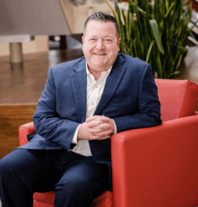 Man in blue suit sitting on a red chair.