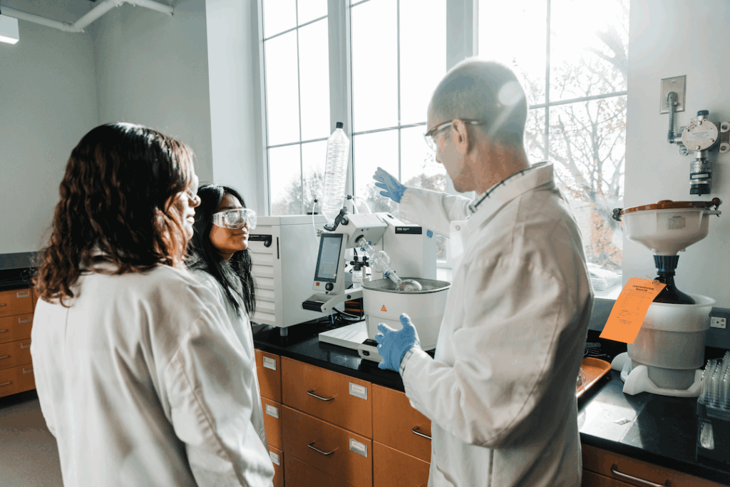 Dr. Mulcahy showing equipment to two students in a lab.