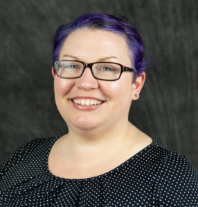 Woman with short blue hair and glasses.