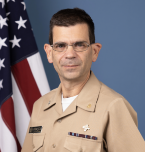 Man with short brown hair and glasses wearing a miliary uniform.