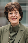 Woman with short brown hair wearing a green suit.